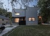 To create visual depth, the entrance of the Thorax House’s gray stucco facade is marked by a black aluminum canopy. The firm created custom signage using red Caesarstone quartz, which was cut using a CNC milling machine. “It’s like a suit with a nice tie,” Aliabadi says. Photo of An Airy Toronto Home with Incredible Double-Height Rooms modern home