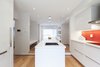 Modern home with Kitchen, Ceiling Lighting, and Medium Hardwood Floor. The polished, matte white glass refrigerator and fridge complement Miele appliances and the IKEA kitchen system. A panel of red-painted glass adds a pop of color. Photo of An Airy Toronto Home with Incredible Double-Height Rooms