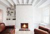 Modern home with Living Room, Chair, Light Hardwood Floor, Wood Burning Fireplace, and Standard Layout Fireplace. The historic apartment has been updated throughout with white paint and minimalist accents, adapting its rustic character to the 21st-century. Photo 5 of Beacon Hill