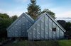Modern home with Exterior, Metal Roof Material, House Building Type, and Metal Siding Material. The studio is located in the natural context of the Scottish coast, with the island of Jura in the distance. A significant design challenge, according to Blake, was “building something quite refined in an extreme and remote environment.” To overcome this logistical obstacle, much of the material was prefabricated offsite and transported to the building location. At the facade, elemental zinc is elevated from raw material to art piece by the unique cladding pattern. The custom embossed standing seam zinc system was designed in collaboration with VM Zinc, and fitted by HLMetals. Photo of Midden Studio