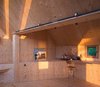 Modern home with Living Room and Light Hardwood Floor. The studio’s artist wanted a workspace that would be a blank canvas. Accordingly, sustainably sourced birch plywood was seamlessly used throughout the interior space. When it becomes weathered, damaged, or covered in paint, it can be easily removed and replaced. Photo 3 of Midden Studio