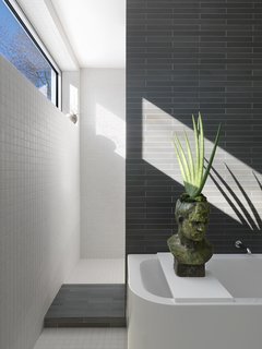 Ann Sacks and American Olean porcelain tile cover every square inch of the master bathroom. Narrow, unevenly spaced rectangular windows are a calling card of the addition and Ronan’s most assertive move. Here the window is a horizontal clerestory, but others are low and vertical.