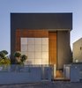 The home’s facade is private and mysterious, without discernable windows or openings. The exterior is made of concrete tiles, black plaster, and wooden trellises. The trellises act as a light screen, allowing only cracks of light to penetrate the exterior. The entry is camouflaged in the plane of the trellises, which adds to the opaque and impenetrable aesthetic at the front facade. Photo of Rishon Le Zion 3 modern home