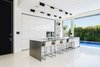 A well-lit and open ground floor with a strong interior-exterior connection was at the top of the family’s wish list. The kitchen makes the most of a compact space through its intimate relationship with the adjacent pool and public outdoor space. The spaces features hardware-free white cabinets and a stainless steel center island. The white kitchen floors provide visual continuity with the white pavement directly outside. Photo 3 of Rishon Le Zion 3 modern home