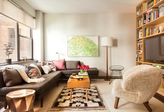 Along with a Dunbar sofa covered in Romo fabric, occasional seating includes a sheepskin Finn Juhl Pelican chair and a vintage wire chair. A BDDW coffee table sits atop a vintage rug. The artwork is by William Steiger.