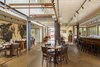 The tables, bar, and booths were also constructed by Peter White. Local craftsman Brian Boggs built the walnut barstools. Photo of A Restaurant Constructed from 19 Salvaged Shipping Containers modern home