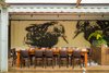 Modern home with Dining Room, Table, and Chair. Local artist Melissa Terrezza painted this mural inside the property. “We have three murals in the containers that she worked on,” said Kristie Quinn, the restaurant owner’s business partner. The building’s lighting is all LEDs from Rexel. Photo of A Restaurant Constructed from 19 Salvaged Shipping Containers