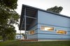 Shelton's team also made sure sustainability went hand-in-hand with affordability. The rainscreen double-wall system with Hardie Panels and the corrugated metal roof reflect sunlight and provide a less expensive, less maintence-intensive house, while strategically placed windows aid cross-ventilation and help cool the home during the humid summer months. The sloped roofs also empty into a rainwater collection system that feeds into the garden. Photo of Habitat for Humanity Home in Kansas Channels Midcentury California modern home