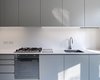 Modern home with Kitchen and Range. Adhering to a budget, it was crucial to use off-the-shelf materials wherever possible. In the kitchen, economical IKEA cabinet frames were dressed up with custom fronts. These doors and drawers were painted with a warmer and darker gray than the floor, adding depth to the space. Both the floors and cabinet surfaces were coated with a subtle sheen to reflect light and create a bright, open feel. Photo of A Compact, Light-Filled Victorian Renovation in England