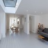 The design team completely changed the layout of the first floor, moving the kitchen to the front of the home and the living room to the rear. The open floor plan allows them to cook in the kitchen while the children play in the living room. All walls and ceilings were painted basic Dulux Brilliant White and a custom-supplied skylight adds illumination to the previously dark and closed-off space. Photo of A Compact, Light-Filled Victorian Renovation in England modern home