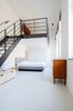 Once a teacher’s lounge, the master bedroom now occupies the first-floor space. A hot rolled steel staircase leads to the lofted second-floor, an addition which brought more livable square footage to the overall program. Photo 3 of The Schoolhouse modern home