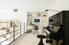 The loft addition afforded space for a home office and music area. The family chose to forego a dedicated office upstairs, instead prioritizing private bedrooms for each of the children. Shelving and a built-in desk anchor the loft’s far wall. Photo 5 of The Schoolhouse modern home