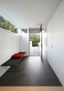 “A series of stepped concrete site walls lead you gradually up to a covered exterior entry, which opens onto a compressed entry foyer,” Hutchison says. A Bertoia bench by Knoll sits in an entryway covered by Mosa’s Greys Collection tiles. Photo 2 of Portage Bay Bungalow modern home