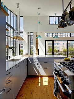 The kitchen is marked by its Wolf gas range, white Carrara marble countertop bar, and Cobb Rise & Fall pendants by Original BTC. The architect designed a custom wine glass holder, which hangs nearby.