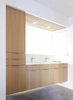 The owners, who describe their design aesthetic as “comfortable minimalism,” envisioned a space with “clean lines, simple materials, and straightforward methods,” an vision shared by Franz and Seth Paré-Mayer. The new master bathroom features custom, locally built rift cut white oak cabinetry, consistent with many of the other spaces on the renovated level. The bathroom vanity floats above polished concrete floors. A bold cutaway was chosen in lieu of an anchoring wall. Unique fold-out mirrors lay flush against the side wall and cabinet when not in use, and swing towards the open center when needed. A custom cast concrete sink by It’s Concrete, Hansgrohe Puravida faucet, and Heath Ceramics soap dish complete the space. Photo 2 of KS Mission modern home