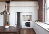 Modern home with Kitchen, White Cabinet, Marble Backsplashe, Marble Counter, Dark Hardwood Floor, Cooktops, and Refrigerator. A floor-to-ceiling wall unit accommodates a fridge, stove, oven, and convertible custom cabinetry. The pendant light is from the Multi Luminaire showroom in Pointe Claire, Quebec; the appliances are from Bosch and Miele. Photo of Brick House