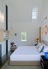 “In this project, the interior walls and ceilings in the existing historical component are white, and the walls and ceiling materials in the new pavilions are wood,” Gurney said. In the master bedroom, a custom bed and nightstands by Baron Gurney Interiors sit across from an Eames molded plywood lounge chair. Photo of A Traditional Facade Hides A Light-Filled Modern Delaware Renovation modern home
