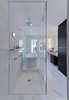 Italian Calacatta Gold marble tiles in the bathroom match an equally pristine Duravit bathtub. Vola fittings were installed in the shower. Photo of A Traditional Facade Hides A Light-Filled Modern Delaware Renovation modern home