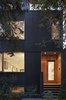 “The house is a three-story volume, but in order to minimize the reading of this volume from the street, we set the walls of the third floor back from the front and rear walls of the building,” Clarkson said. Black wood v-joint siding foils Douglas fir wood cladding around the door. Photo 9 of King West modern home