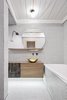 The residents of this maisonette, located in Prague's Vinohrady district, were a young couple returning to the Czech capital after living in London for several years. Stepanova took cues from London's industrial character (with a healthy dash of minimalist design) in devising this remodel's striking aesthetic. In the first bathroom, seen here, a brass washbasin from Morocco is flanked by a Tolomeo Micro Parete lamp from Artemide. Photo of A Sleek Kitchen and Double Bathroom Renovation in Prague modern home