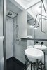 The industrial aesthetic might be strongest in the second of the two bathrooms, where a wireglass shower divider and metal washbasin support were custom fabricated by the Czech workshop kurel. The tap is from Bonigio, the washbasin itself is from Sanindusa, and the lamp is another Tolomeo Micro Parete from Artemide. Photo of A Sleek Kitchen and Double Bathroom Renovation in Prague modern home
