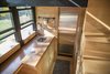 The all-wood interior features standard home appliances, such as a sink, induction cook top, and refrigerator. Photo of A Tiny Trailer Home Harvests Solar Power and Rainwater to Save Energy modern home