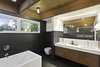 A custom Corian Glacier White countertop finishes a custom vanity made of stained American walnut. Corian also supplied the rectangular sinks, which are topped with Cigno faucets by Lacava. The bathtub is by Zuma, and it stands on a Corian platform. Photo 8 of City Skyline modern home