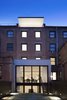 The restored brick rear facade contrasts with the extended footprint of the first two floors and a dramatic cantilevered penthouse roof. Blue stone pavers, infilled with grass, finish the patio while a black steel stair leads to the kitchen. Photo 8 of White Oak modern home