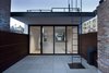 The penthouse level, with its cantilevered overhang, opens to a rooftop entertaining space. The ipe wood cladding, blue stone pavers, and a custom roof ladder are joined by restored brick chimneys. Photo 9 of White Oak modern home
