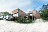 Modern home with Exterior, Beach House Building Type, House Building Type, Flat RoofLine, and Wood Siding Material. The home, clad in natural Australian timber, enjoys a sense of lightness thanks to slender columns that let it float over the dunes. The driveway and entry, at the rear of the building, have an understated design to build to the interior's magnificent ocean views. Firm director Phil Snowdon explains, “By creating an architectural form that draws your eye and leads you up the steep driveway, we could engage new visitors in a welcoming process that first reveals the object and then slowly reveals the main event, being the view." Photo of Martha