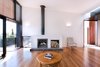 Modern home with Living Room, Wood Burning Fireplace, Standard Layout Fireplace, Medium Hardwood Floor, Chair, Coffee Tables, and Wall Lighting. Eco-friendly features like solar panels and rainwater catchments keep this retreat's environmental footprint small. Immediately to the right of the entry is the main living space, which features a Jetmaster 700D wood-burning fireplace with a tiled hearth. Photo 3 of Martha