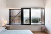 Modern home with Bedroom, Bed, Lamps, Table Lighting, Night Stands, and Medium Hardwood Floor. External shutters and screens allow the homeowners to manage the sunlight and cross ventilation in certain rooms. Manos Mavridis, also of OLA Studio, explains, “There was a preference for the screens to be manually operated to minimize ongoing maintenance costs and encourage user engagement with their environment." Photo 6 of Martha