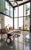 Modern home with Living Room, Chair, Coffee Tables, and Marble Floor. The open-concept main living area, which connects to the dining room and kitchen, is the residents’ favorite part of the home. Soaring ceilings, black aluminum-clad windows, and Carrara marble floors make this central gathering place feel vast. Warm, natural textures are brought in through the Eames molded plywood chairs, brown Mies van der Rohe Barcelona chairs, and natural wooden slab table on steel legs. Photo of A Sustainable Mexican Retreat Made of Raw, Readily Available Materials