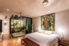 Modern home with Bedroom, Bed, Ceiling Lighting, and Light Hardwood Floor. The emphasis on natural materials continues in the home’s bedrooms. Laminated bamboo flooring and polished concrete walls and ceiling are favored here. A focal point of the room is the the glass-enclosed interior garden, a private extension of the bedroom bordered by a simple cinder block wall. Photo of A Sustainable Mexican Retreat Made of Raw, Readily Available Materials
