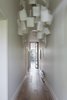 Modern home with Hallway and Medium Hardwood Floor. An Ingo Maurer Zettel’z 5 chandelier hangs in the entry hallway; sunlight from the home's expansive backyard is already visible on the white smoked oak floors. Photo 2 of Seclusion