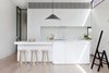 Modern home with Kitchen, White Cabinet, Light Hardwood Floor, Glass Tile Backsplashe, Marble Counter, Undermount Sink, Pendant Lighting, and Range. Black-rimmed steel clerestory windows add illumination in this diminutive white kitchen where black accents abound. A black Aggregato Saliscendi Suspension light, designed by Enzo Mari and Giancarlo Fassina for Artemide, accents against the white Calacatta marble countertops and MAP's oak Milky Stools. Photo 4 of Seclusion