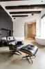When planning the renovation, the owner gave Standard Studio complete freedom to develop the design. In the unconventional bedroom, the bed sits against a black feature wall, with a prominent freestanding bathtub on the opposite side. In addition to the wood beams, all original windows from the old sugar refinery were preserved, to keep the "soul" of the building intact. Photo 3 of Bloemgracht modern home
