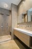 Adjacent to the bedroom, the bathroom features microcement-coated walls, along with a custom sink and vanity. Dornbracht Tara sink faucets and dual rainfall showerheads finish the space. Photo 4 of Bloemgracht modern home