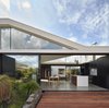 “From the beginning we knew we needed to remove the rear 80s extension and preserve the front Edwardian home,” architect Michael Ong says. “So, we were interested in how the two different architectural styles would work together.” The old Edwardian home can be seen in the center of the frame, through the dining room and kitchen of the addition. Merbau Decking extends into the garden, which became the focal point of the home. Photo of Breeze modern home