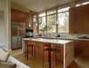 Modern home with Kitchen, Wood Cabinet, Marble Counter, Pendant Lighting, Refrigerator, and Wall Oven. The Bigelows both like to cook and knew from the beginning that a kitchen island was essential. Custom FSC-certified wood cabinets with Makore wood veneer stand over a statuarietto marble countertop and De Sousa Hughes stools. The Cypree pendant lights are from LBL Lighting. Photo of A Couple Puts Their California Home on Track for LEED Certification