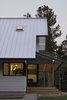 Modern home with Exterior, Metal Roof Material, House Building Type, and Gable RoofLine. “Our goal was to strike a good balance between traditional and modern in a way that did not result in simply a traditional exterior and modern interior,” says Lewis. A pressure-treated wood deck extends from the property under a stained pine, V-groove ceiling. Steel and wood comprise the columns. Photo 3 of The Farmhouse