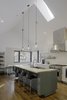 Modern home with Kitchen, Wood Counter, Medium Hardwood Floor, and White Cabinet. “Knowing that the kitchen would be where the family would spend most of their time, it was designed to have a variety of seating and really good views to the beautiful forest and field outside,” says Lewis. IKEA bar stools line up against white quartz countertops, and lighting by Schoolhouse Electric & Supply Co. shines overhead. Photo 4 of The Farmhouse