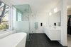 A Rubi bathtub by Ramacieri Soligo was installed beside a shower with Aquabrass finishes. Stone Tile International supplied the Amore porcelain tiles, in graphite black, that spread across the floor. Photo 8 of Art Moderne modern home