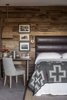 With their neutral tones and natural materials, the rooms feel like an extension of the landscape. "The spectacular area where the property is situated inspired the color palette and materials," Hollis says. "We used reclaimed wood on the walls, simple lighting fixtures, and vintage and found furnishings. All this works together to support the views. It was important to create a seamless transition between indoors and out and make full use of the outdoor living area. Several elements blur this line this such as the outdoor soaking tub, the double sided fireplace that you view from indoors and out, the custom hanging daybed and also the lanterns, which are actually hardwired lighting fixtures."
The leather headboard is from West Elm, the linens are from Frette, the throw blanket is from Pendelton, and the desk is Hollis's own design. Photo of A Serene Hotel in Carmel, California modern home