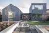 Modern home with Outdoor, Pavers Patio, Porch, Deck, Back Yard, and Grass. The two volumes converge at an exterior courtyard. On the gabled side, skylights bring light into the artist studio; on the cube side, a garden occupies the flat roof. The team used eco-friendly Wet-flash on the roof to draw away moisture from the outside, while allowing a permeable escape for water vapor from the inside. During the estimation and design phases, Dovetail worked closely with Heliotrope to cost engineer and rework elements in order to stay within the client’s budget. The metal roof of the original design was discarded in favor of a simpler and more economical black composite roof. Photo 10 of Central District Residence