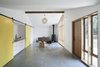 Modern home with Living Room, Concrete Floor, Bar, Chair, Console Tables, Wall Lighting, End Tables, Pendant Lighting, and Wood Burning Fireplace. To evoke the structure’s past as a horse stable, and provide options for the use of the space, Schaer and his team employed Sing Core sliding barn doors mounted on Krownlab’s Axel hardware. The sliding track runs the full width of the building, allowing residents to open or conceal a bedroom, kitchenette, and entrance to an adjacent 530 square-foot garage, all depending on how the spaces are being used. The kitchenette, seen left, features a Kraus sink and a chrome Grohe Concetto faucet. Photo 3 of Horse Stable Studio