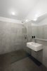Modern home with Bath Room, Open Shower, Concrete Wall, Wall Mount Sink, Concrete Floor, Ceiling Lighting, and Wall Lighting. Milestones' cement plaster covers the walls of the minimalist bathroom. The Scola sink from Duravit is accompanied by a chrome Grohe Essence faucet and Hansgrohe's Croma Green Showerpipe. Photo 8 of Horse Stable Studio