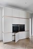 Modern home with Kitchen, Wall Oven, White Cabinet, and Light Hardwood Floor. The opposite wall of the kitchen features built-in Siemens appliances and concealed storage. The custom INTERIOR-iD cabinets feature mitered doors, and brass trim, which passes fluidly around the edge of the doors, terminating at the back wall. Photo of Brass Is Everywhere at this Classical-Meets-Modern Flat in London