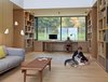 Modern home with Office, Study, Library, Desk, Lamps, Chair, Storage, Bookcase, Shelves, and Medium Hardwood Floor. The lower submerged level is comprised of the kids’ and guest bedrooms as well as the multi-purpose room—is a popular hangout for the kids and family dog, Roxy. The Chair and Bar Bench, both by Hans Wegner for PP Møbler, a Muuto 3-seater sofa by Andersen & Voll, and David Weeks' Tripod No. 303 floor lamp mix midcentury modern with contemporary design. Photo of 17 Modern Homes With Hans Wegner Furniture