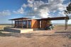 Modern home with House, Metal Roof Material, Metal Siding Material, Outdoor, Desert, Small Patio, Porch, Deck, Shrubs, and Concrete Patio, Porch, Deck. The house has two modules: a living space on the left and a utilities, laundry, and outdoor kitchen on the right. Photo of Petite Prefab with Stunning Views of the Texas Landscape